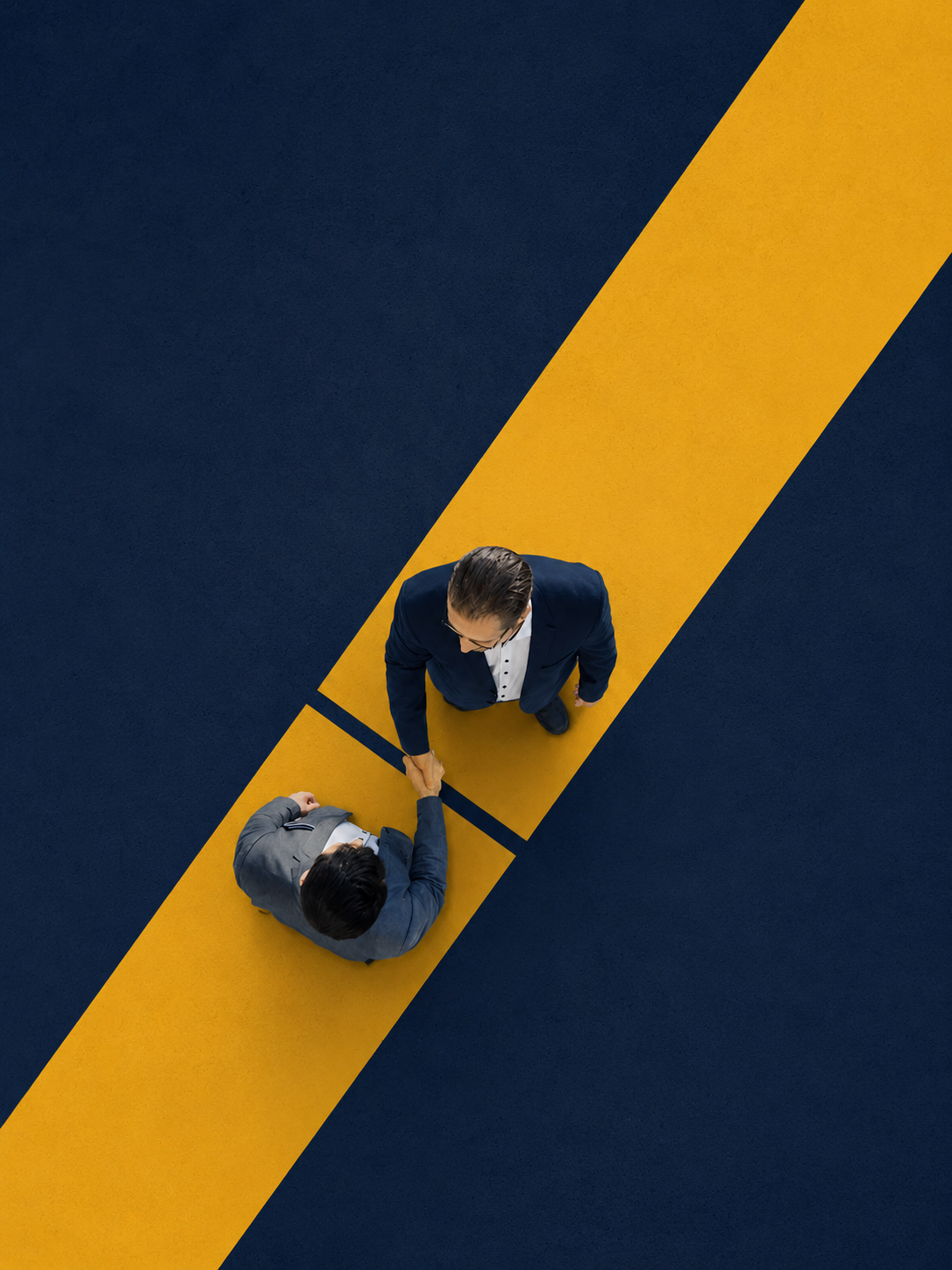 Overhead view of two professionals shaking hands across a yellow path on deep navy ground